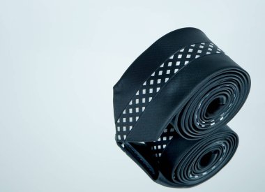 Yansıma yüzeyi üzerinde yuvarlanan bir kravat. Yakından tek bir nesne görüntüsü 