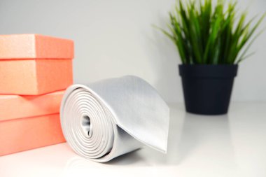 Hediye kutusuyla sarılmış düz kumaştan beyaz kravat. Yakın çekim. 