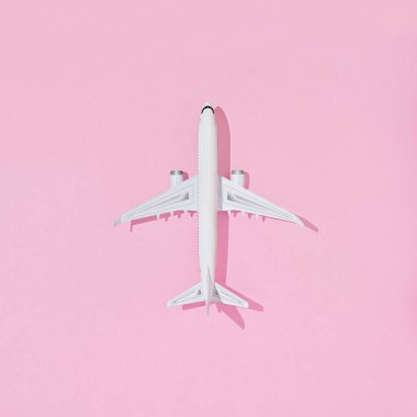 Pastel renkli arka planda düz dizayn edilmiş uçak. Seyahat ya da tatil konsepti. Pastel pembe arka planda yolcu uçağıyla yapılan yaratıcı kompozisyon üzerine üst görünüm.