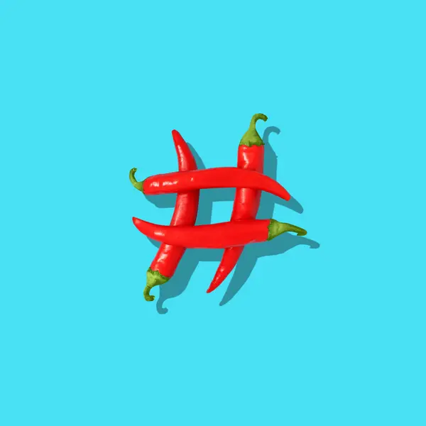 Hashtag sign symbol made from red peppers on vivid blue blue background, copy space. Negative space to insert your text. Modern design. Contemporary art. Creative conceptual and colorful collage.