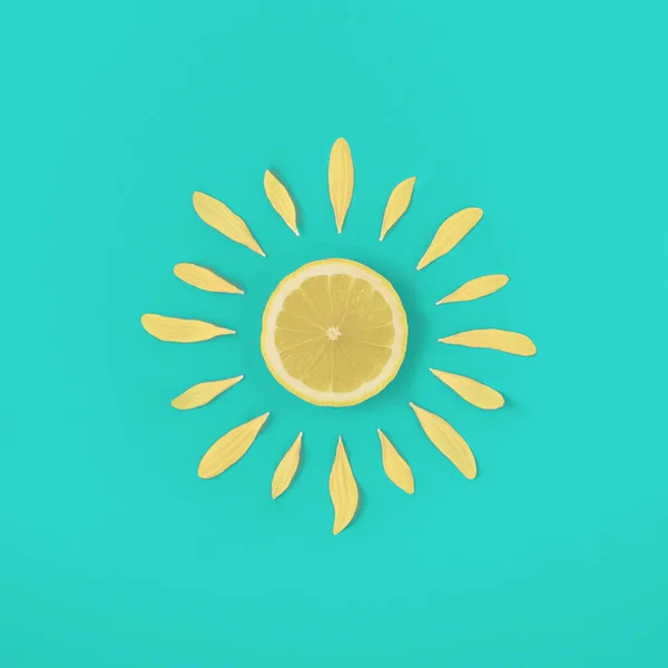 Sun made of lemon and yellow flower petals on bright blue background. Fruit summer minimal concept.Summer creative art. Minimal citrus fruits aesthetic.