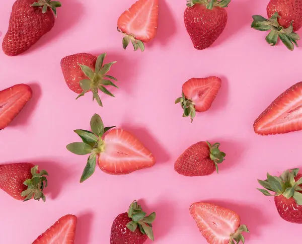 Pembe arka planda çileklerden yapılmış yaratıcı bir düzen. Düz yatıyordu. Meyve konsepti. Gıda düzeni.