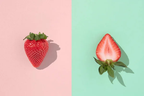 一个完整的和一片草莓片在一个粉红和茶色的绿色背景与锐利的阴影 最低夏季概念 — 图库照片