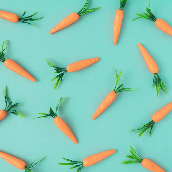 Paskalya deseni parlak mavi arka planda havuçlarla yapılır. Yaratıcı Paskalya bayramı konsepti. Minimum bahar tatili tebrik kartı ya da fikri. Düz yatıyordu.