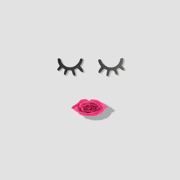 Creative woman face made of eyelashes and red rose flower lips. Minimal beauty concept. Flat lay.