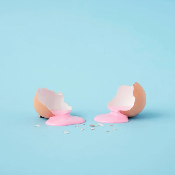Modern Abstract easter composition with Eggshell ,pastel pink paint.and copy space on pastel blue background. Minimal Easter holiday concept. Creative art minimal aesthetics.