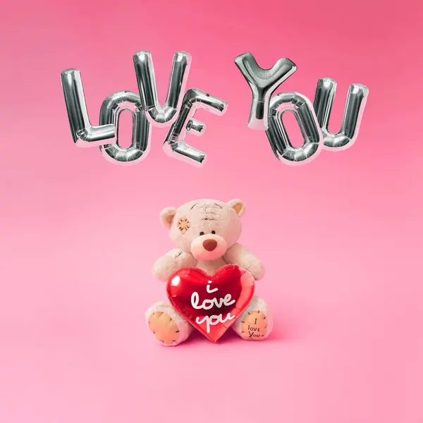 Love composition made of teddy bear, heart and Foil Balloons in the shape of the word 