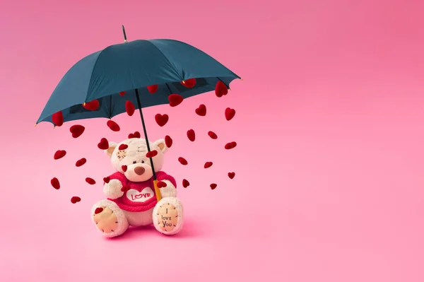Love composition made of teddy bear, umbrella and rain in the shape of a heart on pastel pink background. Minimal concept of Valentine\'s Day or love. Creative art, minimal aesthetics.