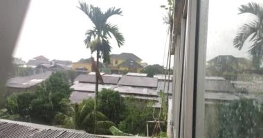 Evlerin çatıları ve yeşil ağaçlar gün boyunca sağanak yağış altında kalıyor, yağmur videoları 4K çözünürlükte çekiliyor.
