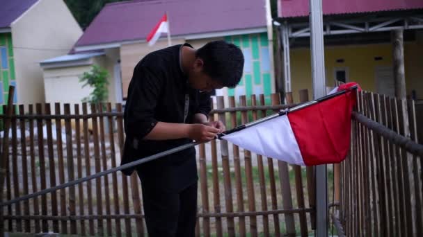 若いアジア人男性がインドネシアの独立記念日を祝うためにインドネシアの国旗を掲げています インドネシアの国旗は赤と白の旗 — ストック動画