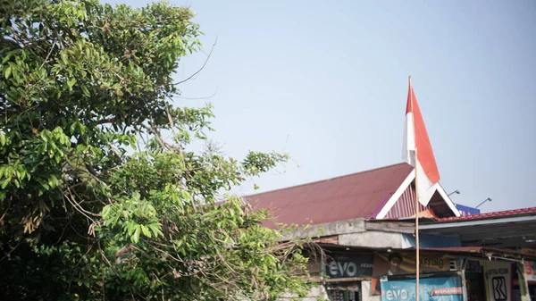 印度尼西亚独立日的背景是 红色和白色的国旗在旗杆上迎着晴朗的天空飘扬 — 图库照片