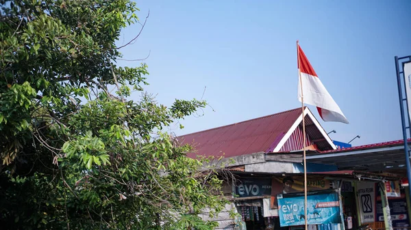 背景がインドネシアの独立記念日を歓迎する明確な空に対してポールの上に赤と白の旗 — ストック写真