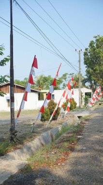 Yol kenarındaki bambu direkleri üzerinde süslü kırmızı ve beyaz bayraklar - umbul olarak da bilinir - umbul, kırmızı ve beyaz bayrak Endonezya bağımsızlık gününü karşılıyor