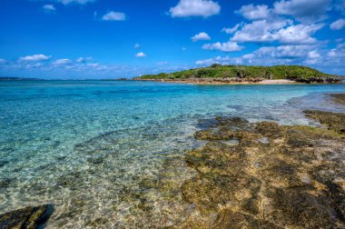 Okinawa 'daki Motobu Bölgesi, Bise Plajı' nın berrak suları. Mercan çıkıntılı beyaz kumsal ve açık denizde küçük adalar.