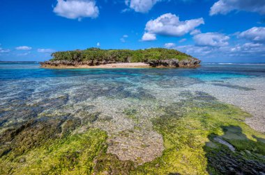 Okinawa 'daki Motobu Bölgesi, Bise Plajı' nın berrak suları. Mercan çıkıntılı beyaz kumsal ve açık denizde küçük adalar.