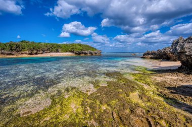 Okinawa 'daki Motobu Bölgesi, Bise Plajı' nın berrak suları. Mercan çıkıntılı beyaz kumsal ve açık denizde küçük adalar.