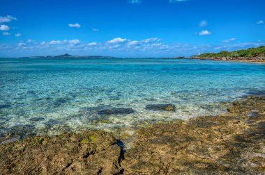 Okinawa 'daki Motobu Bölgesi, Bise Plajı' nın berrak suları. Mercan çıkıntılı beyaz kumsal ve açık denizde küçük adalar.