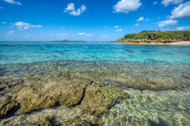 Okinawa 'daki Motobu Bölgesi, Bise Plajı' nın berrak suları. Mercan çıkıntılı beyaz kumsal ve açık denizde küçük adalar.