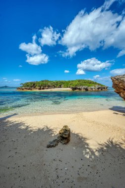 Okinawa 'daki Motobu Bölgesi, Bise Plajı' nın berrak suları. Mercan çıkıntılı beyaz kumsal ve açık denizde küçük adalar.