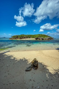 Okinawa 'daki Motobu Bölgesi, Bise Plajı' nın berrak suları. Mercan çıkıntılı beyaz kumsal ve açık denizde küçük adalar.