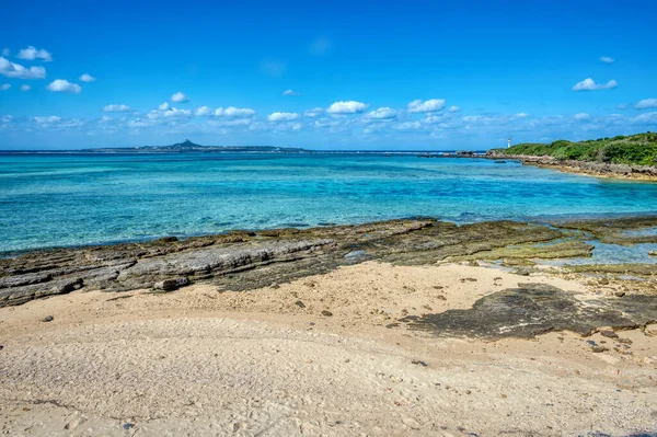 Okinawa 'daki Motobu Bölgesi, Bise Plajı' nın berrak suları. Mercan çıkıntılı beyaz kumsal ve açık denizde küçük adalar.