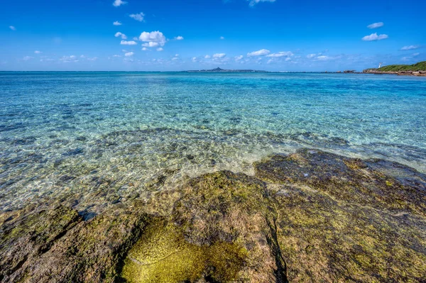 Okinawa 'daki Motobu Bölgesi, Bise Plajı' nın berrak suları. Mercan çıkıntılı beyaz kumsal ve açık denizde küçük adalar.