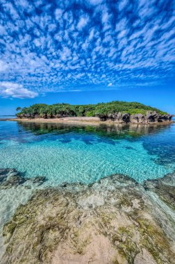 Okinawa 'daki Motobu Bölgesi, Bise Plajı' nın berrak suları. Mercan çıkıntılı beyaz kumsal ve açık denizde küçük adalar..