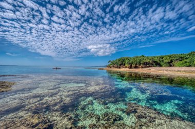 Okinawa 'daki Motobu Bölgesi, Bise Plajı' nın berrak suları. Mercan çıkıntılı beyaz kumsal ve açık denizde küçük adalar..