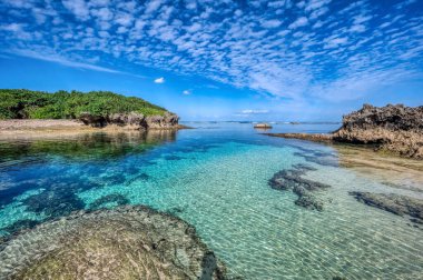 Okinawa 'daki Motobu Bölgesi, Bise Plajı' nın berrak suları. Mercan çıkıntılı beyaz kumsal ve açık denizde küçük adalar..