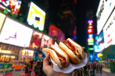 New York 'ta Times Meydanı' nda iki sosisli sandviç tutuyor. .