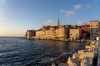 Sıcak güneş ışığı Adriyatik denizi ve kayalarla Rovinj şehrini vurdu. .