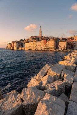 Sıcak güneş ışığı Adriyatik denizi ve kayalarla Rovinj şehrini vurdu. .