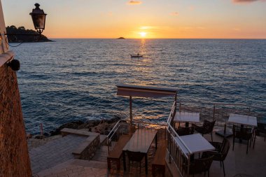 Rovinj Riva 'da gün batımında Adriyatik Denizi ve taş merdivenleri ve canlandırıcı masası .