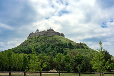 Sumeg castle on the hill in Hungary springtimewith green trees . clipart