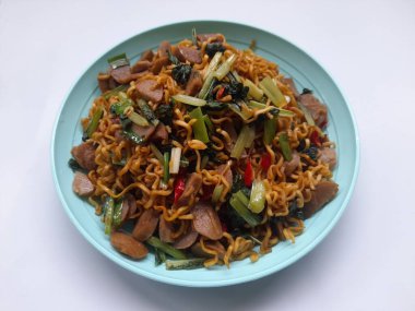 Kızarmış şehriye (mie goreng) beyaz arka planda bir tabak üstünde. Kahvaltı, öğle yemeği, akşam yemeği, fast food, yaşam tarzı, mutfak, mutfak, yemek, atıştırma, yemek tarifi