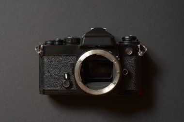 Merceksiz, metal lens montajı, desenli siyah tasarım ve klasik analog kontrolleri gösteren klasik bir kamera gövdesinin ön görüntüsü.