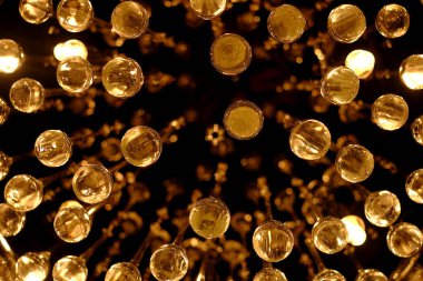 Soyut altın kürelerin yakın plan çekimleri, koyu arkaplanda sıcak ve parlak yansımalar. Lüks, kutlama ya da şenlikli tasarım kavramı.