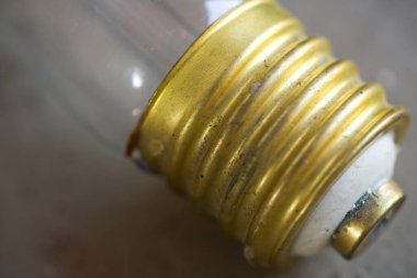 Eski bir 300W akkor ampulden, başlıklı metal vida temeli yakın çekim makrosu, tecure ve detay gösteren vintage elektrik bileşeni.