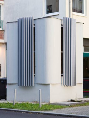 Detail of a ventilation or technical shaft with vertical metal louvers in front of a residental building. Example of urban infrastructure and architectural design.