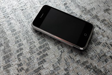 Zbrasav, Czech Republic - April 8, 2018: Editorial photograph of the first generation Apple iPhone 2G on stone pavement texture background. Editorial use only.