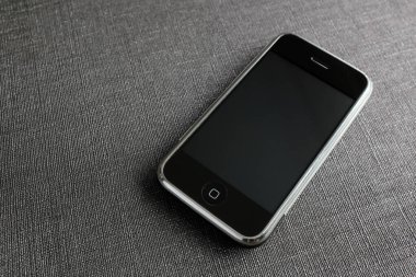 Zbrasav, Czech Republic - April 8, 2018: Editorial photograph of the first generation Apple iPhone 2G on gray textured fabric background. Editorial use only.