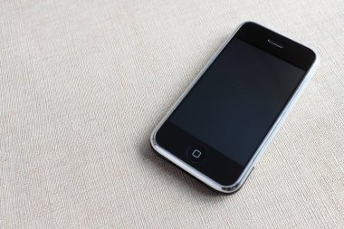 Zbrasav, Czech Republic - April 8, 2018: Editorial photograph of the first generation Apple iPhone 2G on beige textile fabric background. Editorial use only.