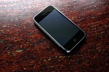 Zbrasav, Czech Republic - April 8, 2018: Editorial photograph of the first generation Apple iPhone 2G on reddish brown wooden textured background. Editorial use only.