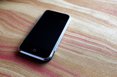 Zbrasav, Czech Republic - April 8, 2018: Editorial photograph of the first generation Apple iPhone 2G on abstract painted background with red and yellow accents. Editorial use only.