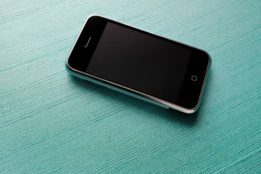 Zbrasav, Czech Republic - April 8, 2018: Editorial photograph of the first generation Apple iPhone 2G on turquoise textile background. Editorial use only.