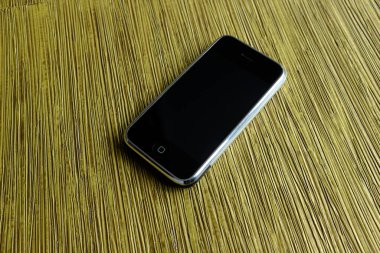 Zbrasav, Czech Republic - April 8, 2018: Editorial photograph of the first generation Apple iPhone 2G on yellow textile fabric background. Editorial use only.