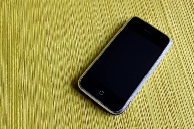 Zbrasav, Czech Republic - April 8, 2018: Editorial photograph of the first generation Apple iPhone 2G on yellow textile fabric background. Editorial use only.