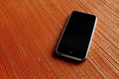 Zbrasav, Czech Republic - April 8, 2018: Editorial photograph of the first generation Apple iPhone 2G on dark orange textile fabric babckground. Editorial use only.