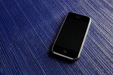 Zbrasav, Czech Republic - April 8, 2018: Editorial photograph of the first generation Apple iPhone 2G on blue textile fabric background. Editorial use only.