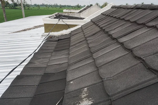 The black zinc roof of the house is dented by the heavy rain